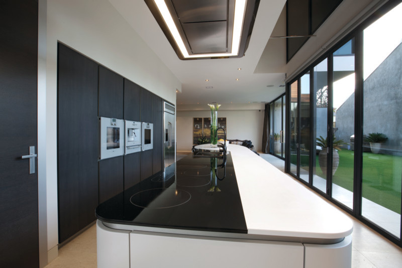 Design ideas for a contemporary galley eat-in kitchen in Melbourne with an integrated sink, flat-panel cabinets, dark wood cabinets, solid surface benchtops and stainless steel appliances.