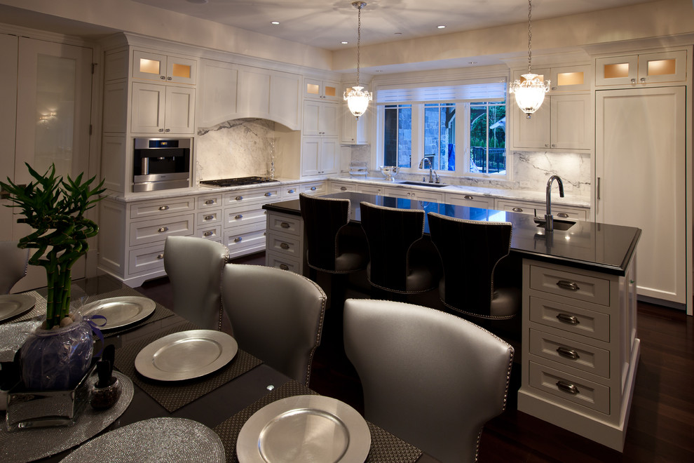 Expansive traditional l-shaped eat-in kitchen in Vancouver with an undermount sink, recessed-panel cabinets, white cabinets, granite benchtops, multi-coloured splashback, panelled appliances and with island.