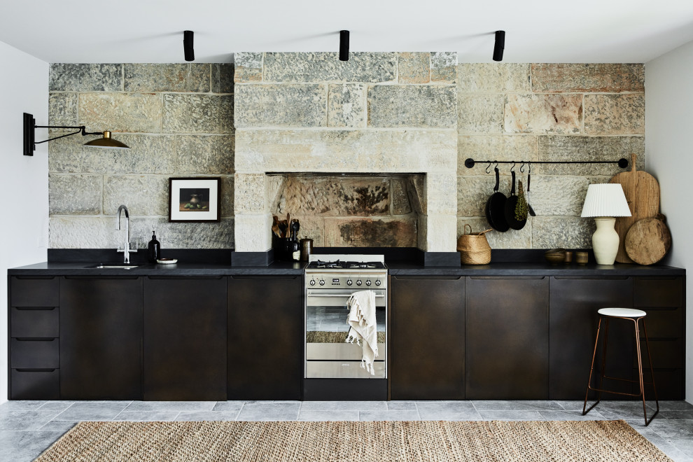 Idéer för att renovera ett stort lantligt svart linjärt svart kök med öppen planlösning, med en undermonterad diskho, släta luckor, bruna skåp, marmorbänkskiva, svart stänkskydd, stänkskydd i skiffer, rostfria vitvaror, kalkstensgolv och grått golv