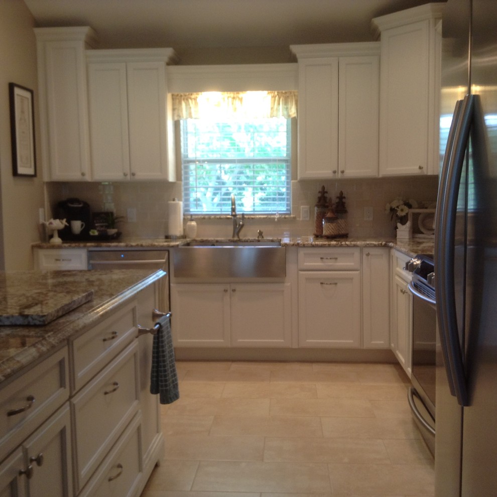 Example of a mid-sized transitional l-shaped medium tone wood floor and brown floor eat-in kitchen design in Orlando with a farmhouse sink, recessed-panel cabinets, white cabinets, granite countertops, white backsplash, subway tile backsplash, stainless steel appliances and an island
