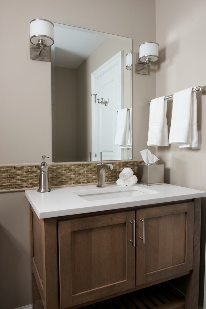 Inspiration for a mid-sized transitional beige tile and ceramic tile beige floor powder room remodel in New York with recessed-panel cabinets, medium tone wood cabinets, an undermount sink, solid surface countertops and white countertops