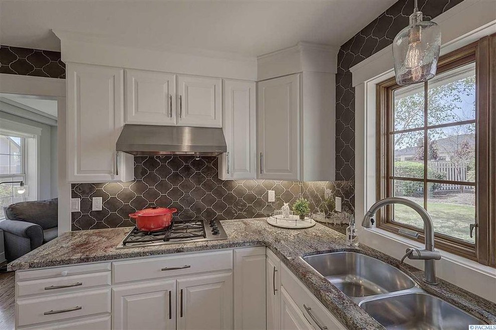 Transitional u-shaped medium tone wood floor and brown floor eat-in kitchen photo in Seattle with an undermount sink, raised-panel cabinets, white cabinets, granite countertops, brown backsplash, porcelain backsplash, stainless steel appliances and brown countertops