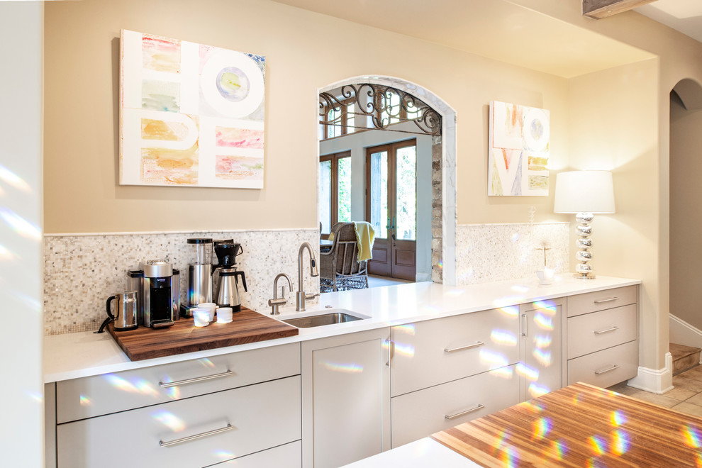 Enclosed kitchen - mid-sized transitional ceramic tile and brown floor enclosed kitchen idea with an undermount sink, flat-panel cabinets, beige cabinets, quartzite countertops, white backsplash, ceramic backsplash, stainless steel appliances, two islands and white countertops