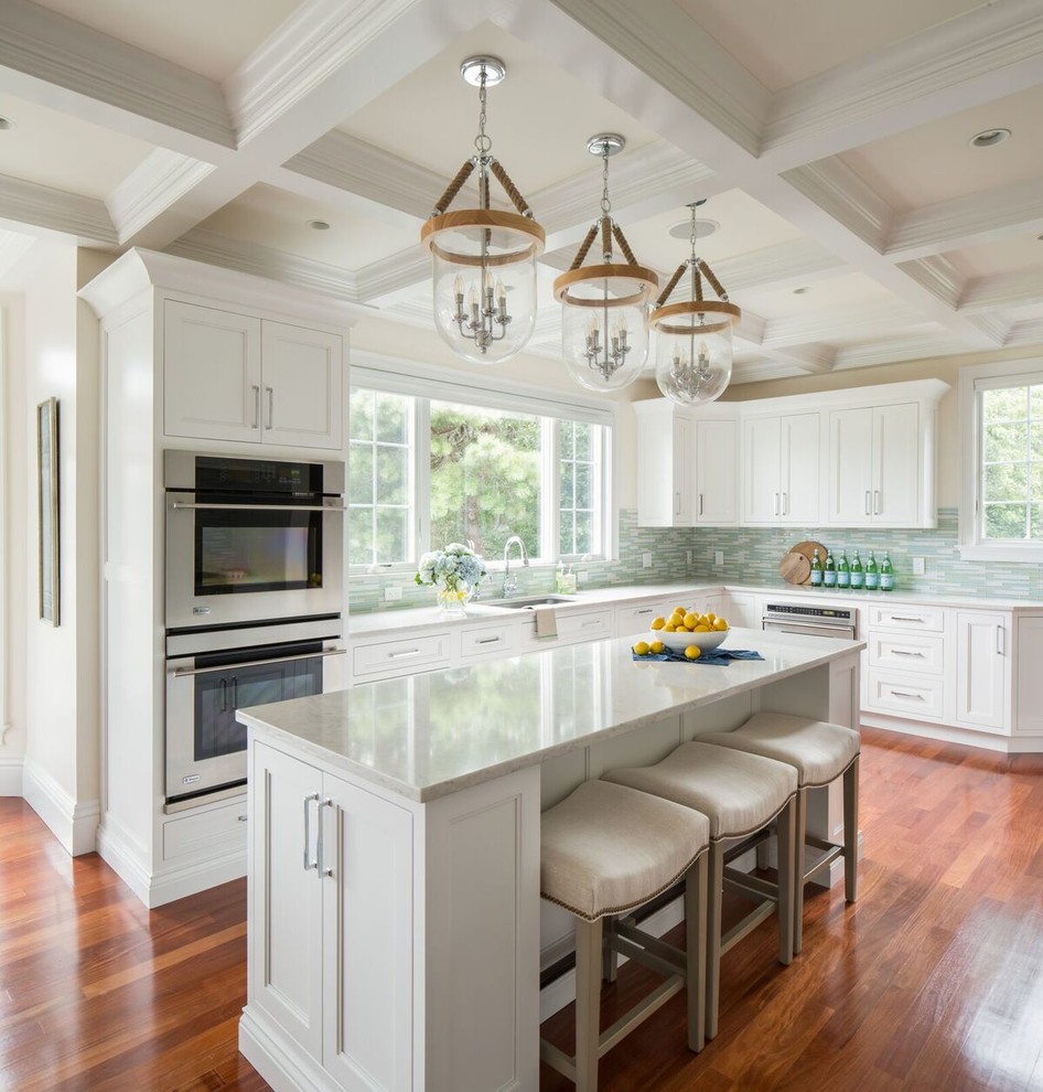This is an example of a large traditional l-shaped eat-in kitchen in Boston with an undermount sink, recessed-panel cabinets, white cabinets, marble benchtops, blue splashback, glass tile splashback, stainless steel appliances, with island and medium hardwood floors.