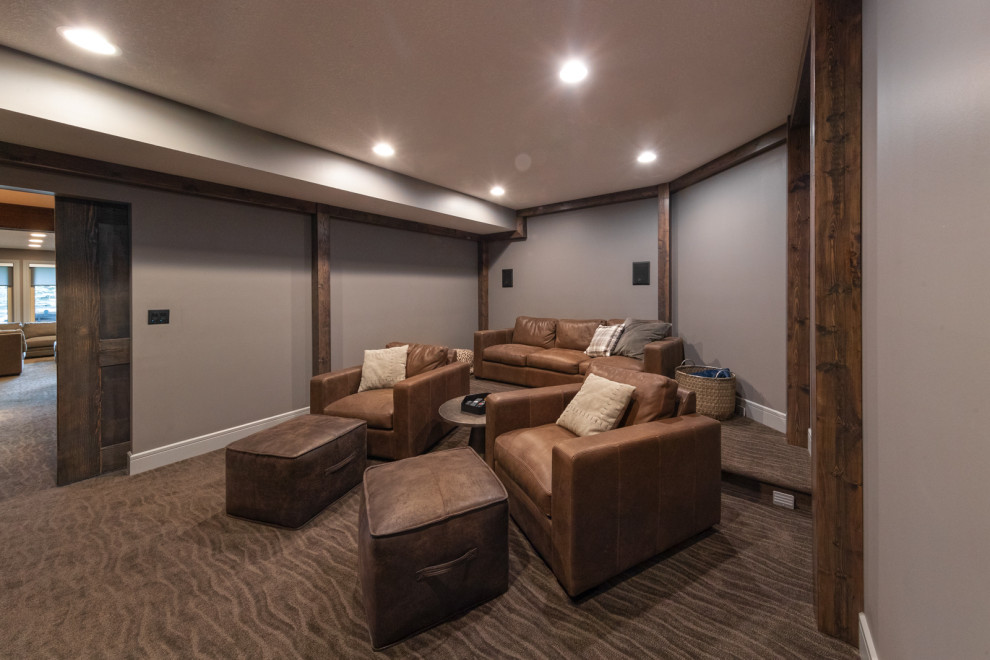 Modelo de cine en casa cerrado actual de tamaño medio con paredes grises, moqueta, televisor colgado en la pared y suelo marrón