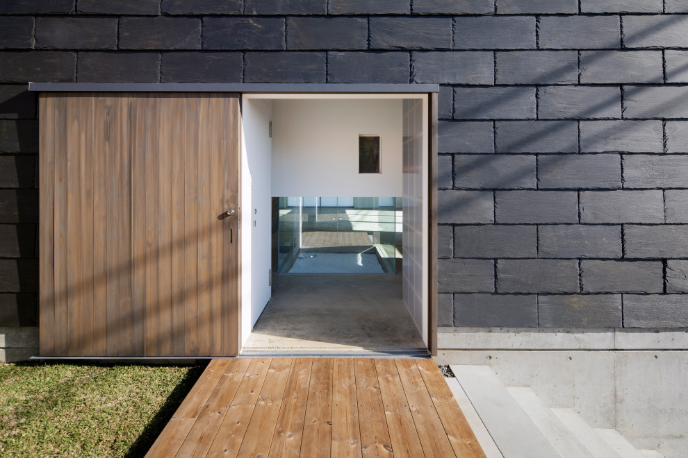 Diseño de fachada de casa negra asiática de dos plantas con revestimiento de piedra y escaleras