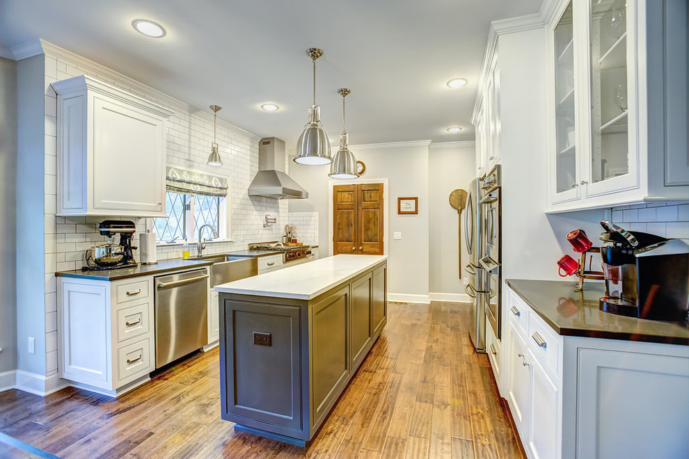 Mid-sized transitional galley medium tone wood floor eat-in kitchen photo in Birmingham with a farmhouse sink, shaker cabinets, white cabinets, quartz countertops, white backsplash, subway tile backsplash, stainless steel appliances and an island