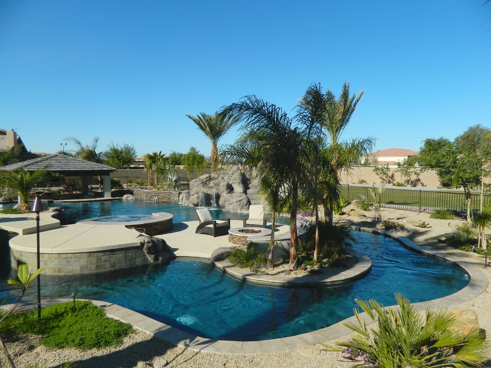 Design ideas for a large mediterranean backyard custom-shaped natural pool in Phoenix with natural stone pavers.