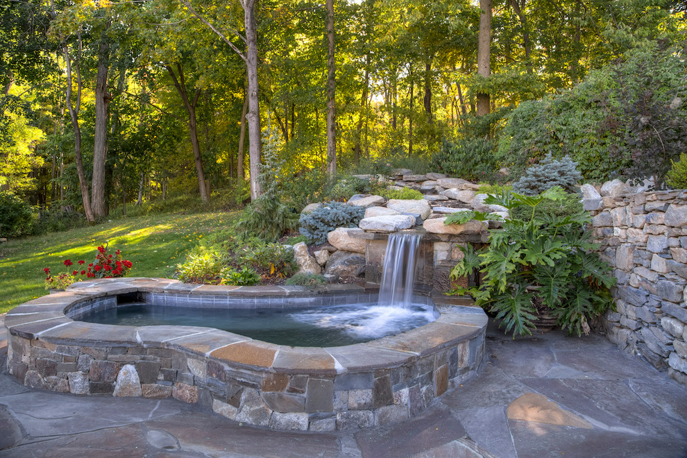 Example of a small classic backyard stone and kidney-shaped natural hot tub design in New York