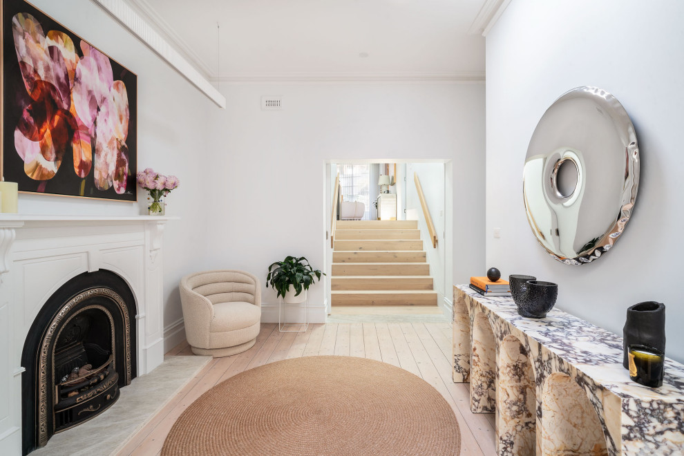 This is an example of a small contemporary foyer in Melbourne with white walls, light hardwood floors and beige floor.