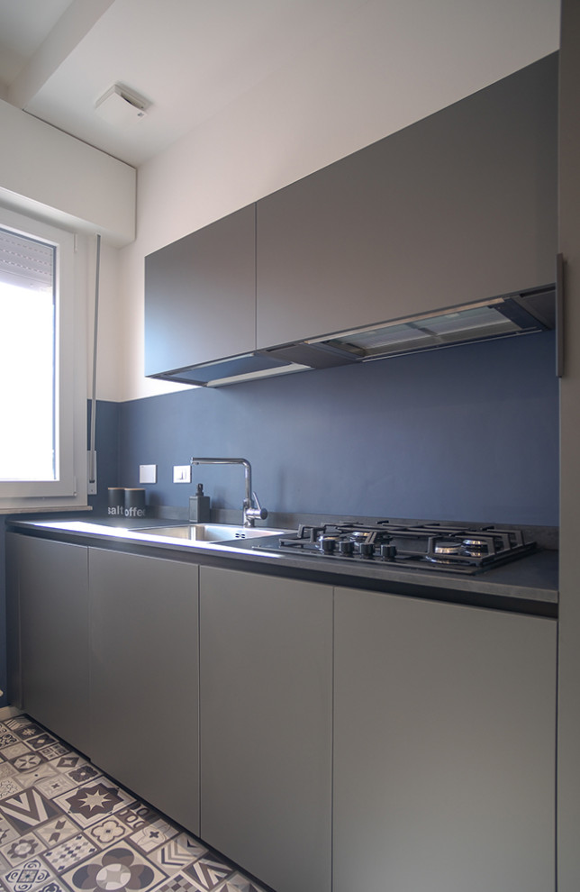 Foto di una cucina minimal chiusa e di medie dimensioni con lavello da incasso, ante lisce, ante grigie, paraspruzzi blu, pavimento in cementine, top grigio e parquet e piastrelle