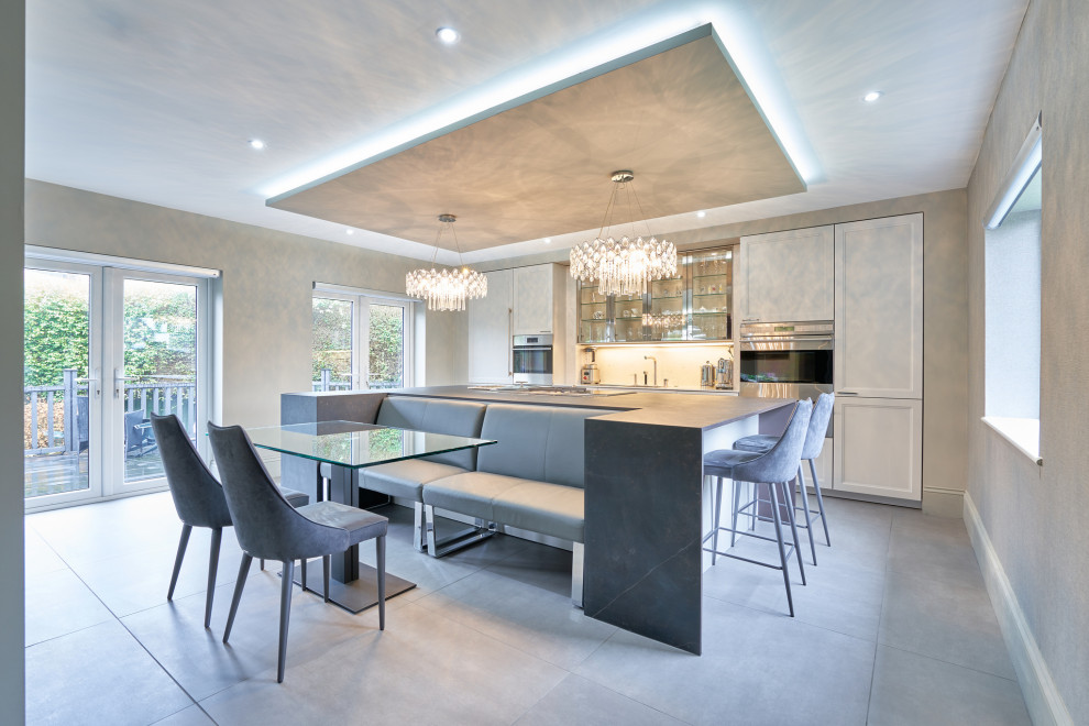 Inspiration for a large contemporary galley eat-in kitchen in Hampshire with an undermount sink, recessed-panel cabinets, white cabinets, panelled appliances, with island, grey floor and grey benchtop.