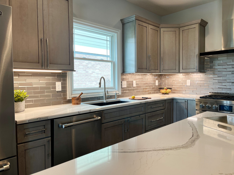 Mid-sized transitional l-shaped dark wood floor and brown floor eat-in kitchen photo with an undermount sink, gray cabinets, quartz countertops, glass tile backsplash, stainless steel appliances, an island, beige countertops and white backsplash