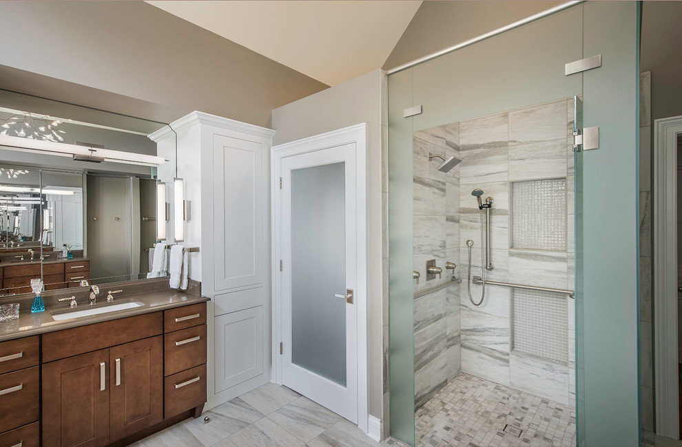 Large contemporary master bathroom in Cleveland with shaker cabinets, medium wood cabinets, brown tile, stone slab, solid surface benchtops, a drop-in tub, a curbless shower, a two-piece toilet, beige walls, marble floors and an undermount sink.