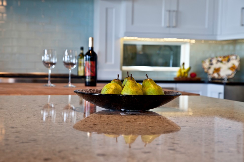 Eat-in kitchen - large transitional l-shaped medium tone wood floor and brown floor eat-in kitchen idea with a farmhouse sink, shaker cabinets, white cabinets, quartzite countertops, blue backsplash, glass sheet backsplash, stainless steel appliances and an island
