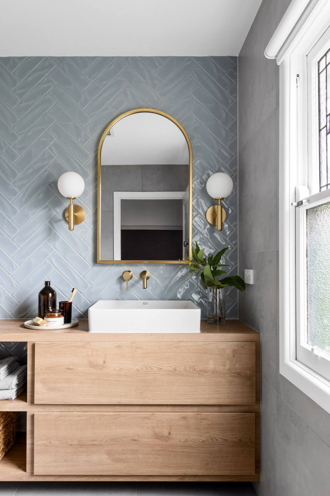 Inspiration for a mid-sized modern 3/4 bathroom in Melbourne with flat-panel cabinets, light wood cabinets, an open shower, a wall-mount toilet, blue tile, cement tile, grey walls, cement tiles, a vessel sink, wood benchtops, grey floor, an open shower, brown benchtops, a niche, a single vanity and a floating vanity.