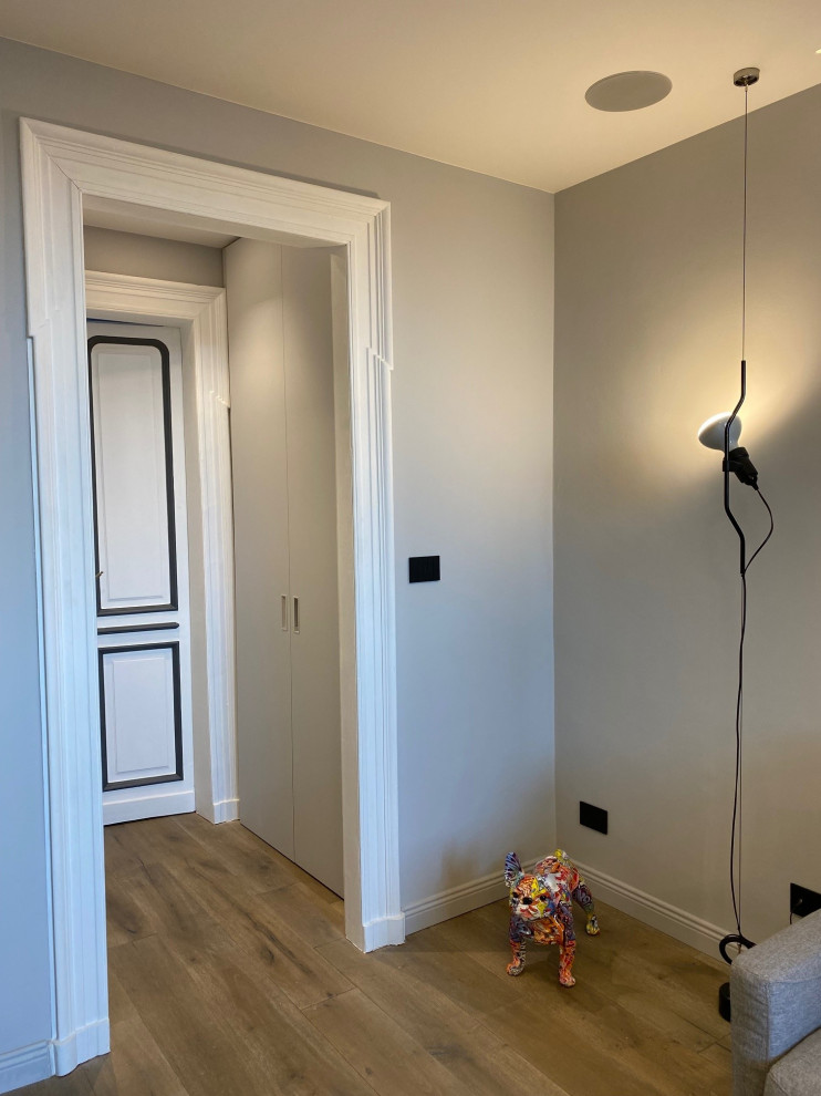 Photo of a small industrial single-wall utility room in Turin with flat-panel cabinets, grey cabinets, grey walls, dark hardwood flooring, a stacked washer and dryer, brown floors and a drop ceiling.