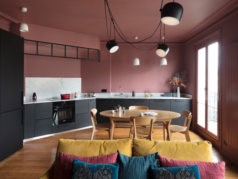 This is an example of an expansive contemporary single-wall open plan kitchen in Paris with black cabinets, marble benchtops, marble splashback, flat-panel cabinets, grey splashback, medium hardwood floors, no island, brown floor and grey benchtop.