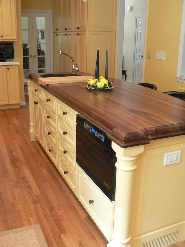 This is an example of a large traditional u-shaped kitchen in DC Metro with an undermount sink, raised-panel cabinets, yellow cabinets and with island.