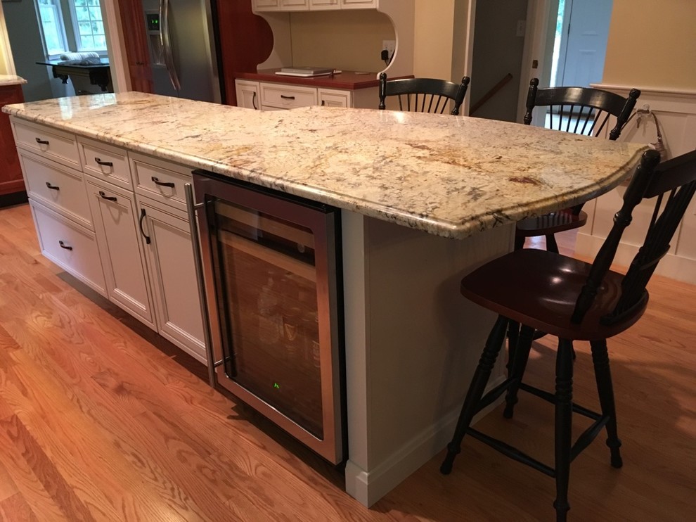 Transitional u-shaped light wood floor eat-in kitchen photo in Boston with an undermount sink, raised-panel cabinets, granite countertops, subway tile backsplash, stainless steel appliances and an island