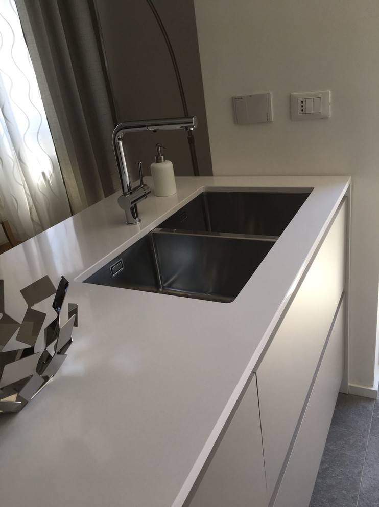 Inspiration for a mid-sized modern galley open plan kitchen in Rome with an undermount sink, flat-panel cabinets, grey cabinets, quartz benchtops, white appliances, light hardwood floors, with island, brown floor and white benchtop.
