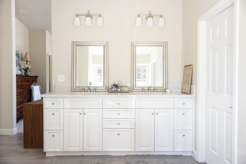 Photo of a mid-sized country master bathroom in San Luis Obispo with raised-panel cabinets, white cabinets, beige walls, porcelain floors, a drop-in sink, engineered quartz benchtops, grey floor and white benchtops.