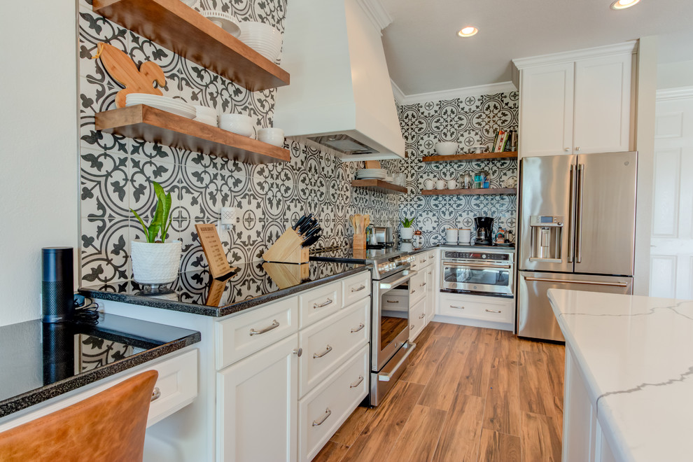 Large transitional l-shaped ceramic tile and brown floor eat-in kitchen photo with an undermount sink, shaker cabinets, white cabinets, quartz countertops, multicolored backsplash, ceramic backsplash, stainless steel appliances, an island and white countertops