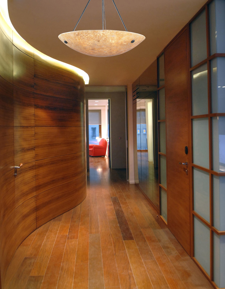 Hallway - huge medium tone wood floor hallway idea in New York with brown walls