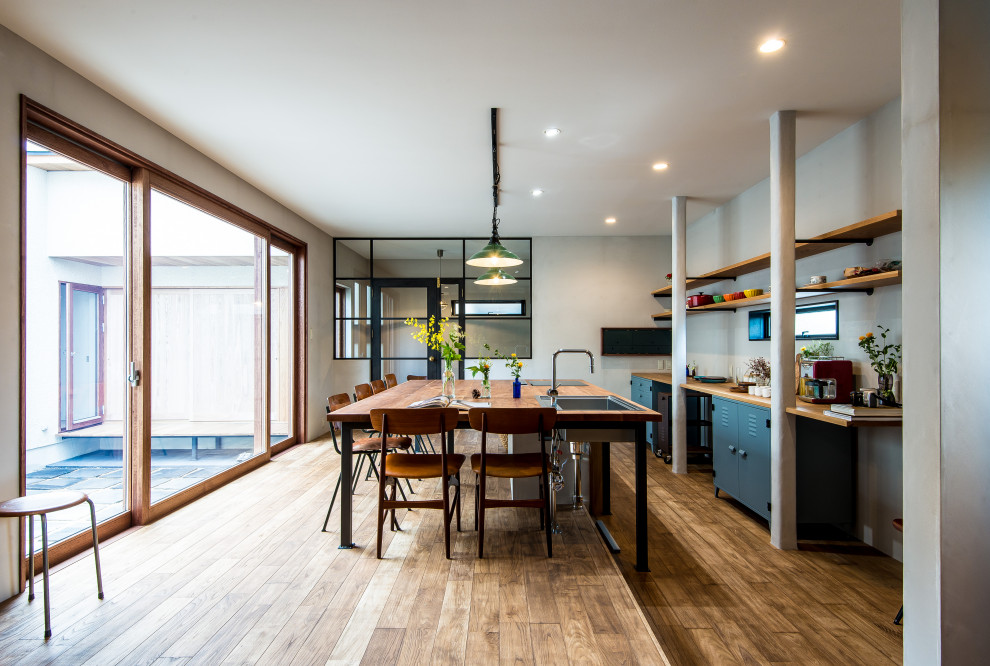 Industrial Küche mit offenen Schränken, blauen Schränken, Arbeitsplatte aus Holz, braunem Holzboden und Kücheninsel in Sonstige