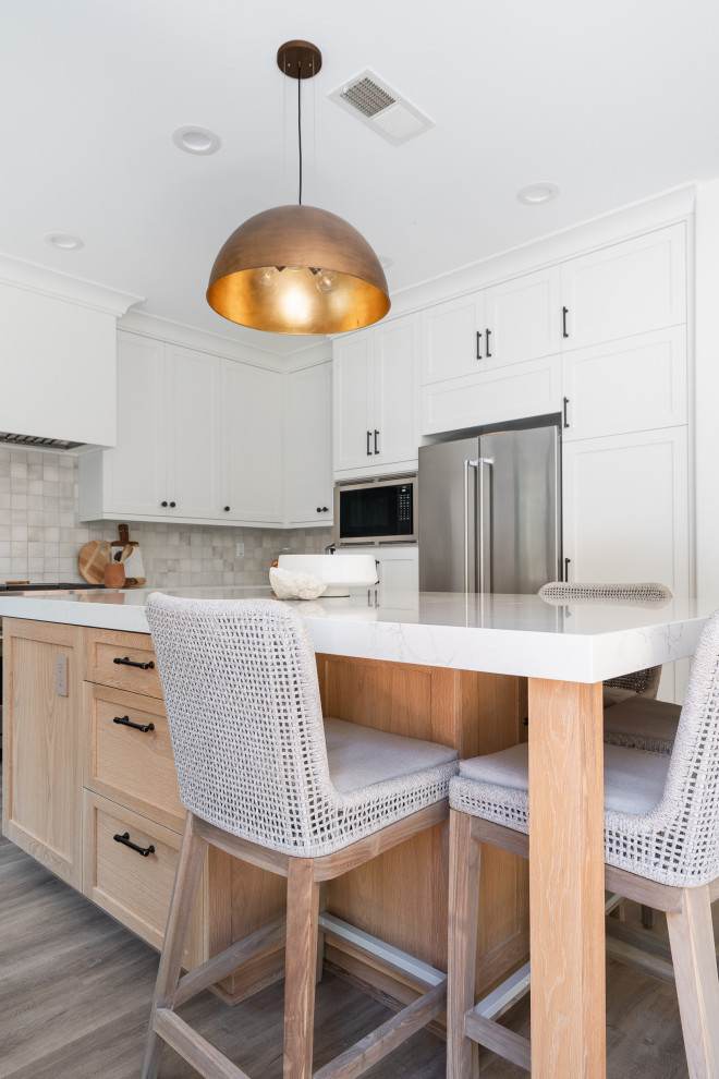 Large beach style u-shaped vinyl floor and beige floor open concept kitchen photo in Denver with an undermount sink, recessed-panel cabinets, light wood cabinets, quartz countertops, white backsplash, ceramic backsplash, stainless steel appliances, an island and white countertops