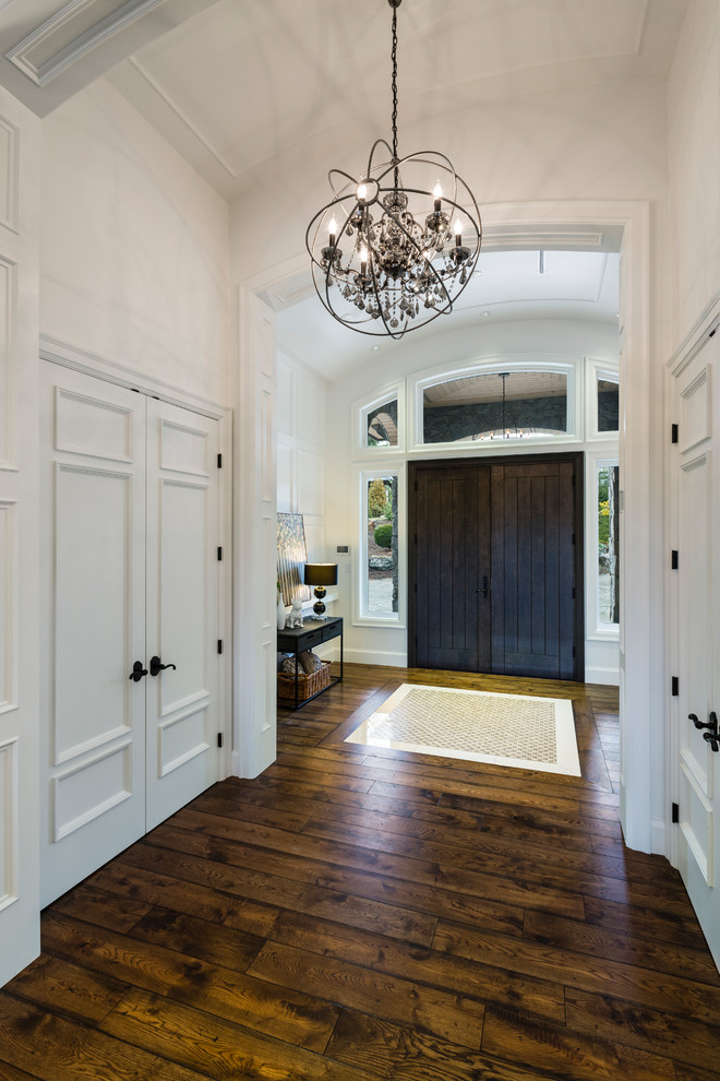 Foyer - huge rustic medium tone wood floor and brown floor foyer idea in Vancouver with white walls and a dark wood front door