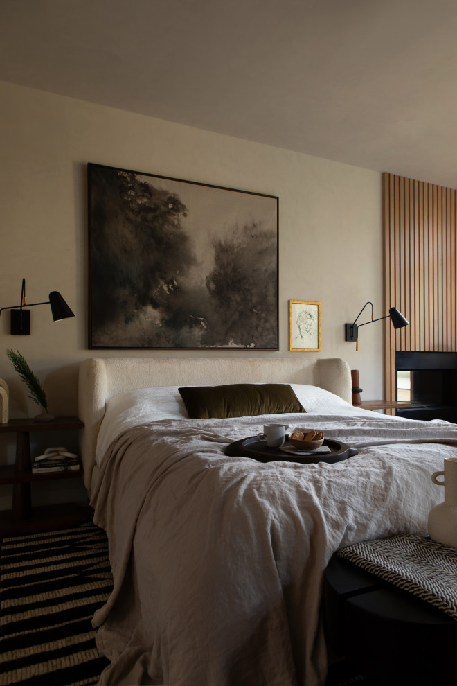Идея дизайна: хозяйская спальня среднего размера в современном стиле с бежевыми стенами, ковровым покрытием, разноцветным полом, угловым камином и фасадом камина из дерева