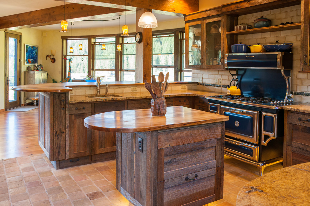 Example of a large mountain style u-shaped cement tile floor and beige floor open concept kitchen design in Seattle with recessed-panel cabinets, granite countertops, beige backsplash, ceramic backsplash, stainless steel appliances, an island, dark wood cabinets and an undermount sink