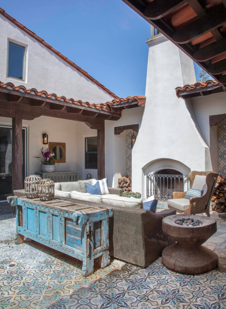 Mediterranean patio in San Diego with with fireplace, tile and no cover.