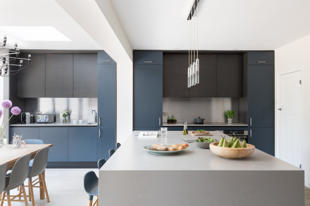 This is an example of a large contemporary eat-in kitchen in Sussex with a drop-in sink, flat-panel cabinets, dark wood cabinets, solid surface benchtops, metallic splashback, stainless steel appliances, medium hardwood floors, with island, grey floor and grey benchtop.