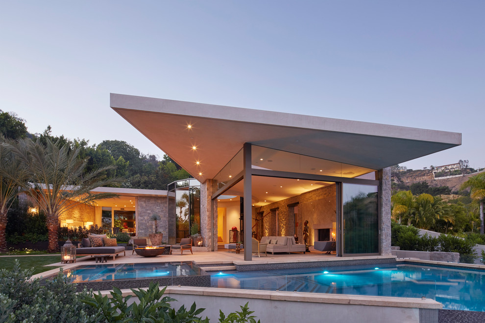 Photo of an expansive contemporary one-storey grey exterior in Los Angeles with stone veneer and a flat roof.