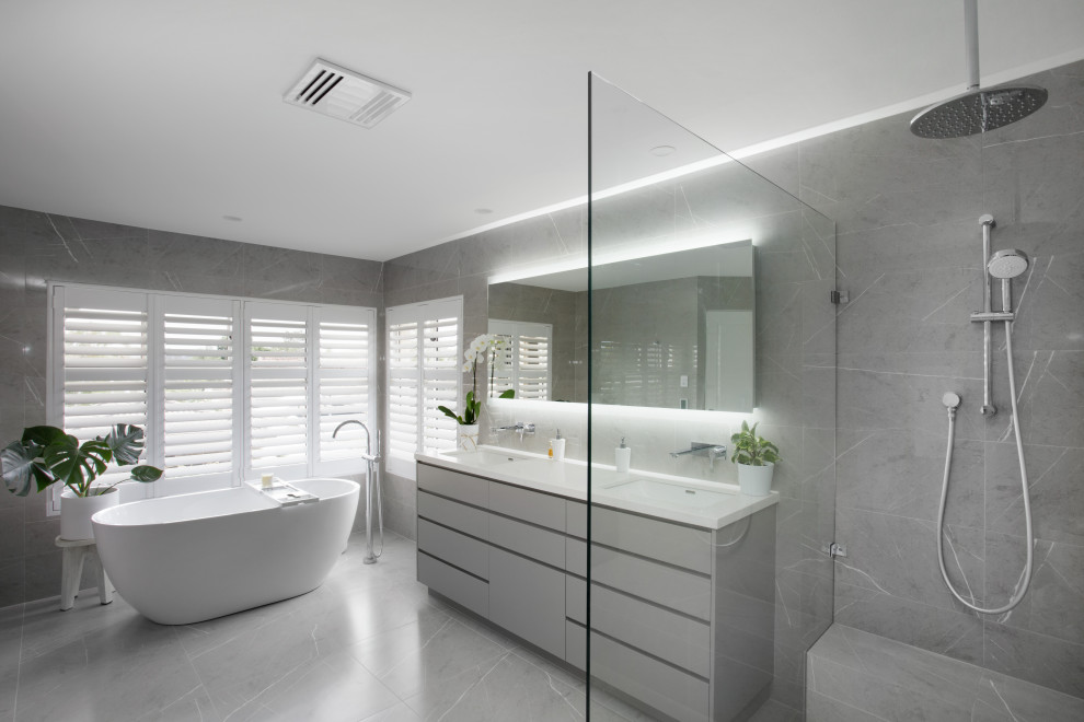 Design ideas for a large contemporary master bathroom in Brisbane with grey cabinets, a freestanding tub, an open shower, gray tile, ceramic tile, grey walls, ceramic floors, an undermount sink, engineered quartz benchtops, grey floor, an open shower, white benchtops, a shower seat, a double vanity and a built-in vanity.