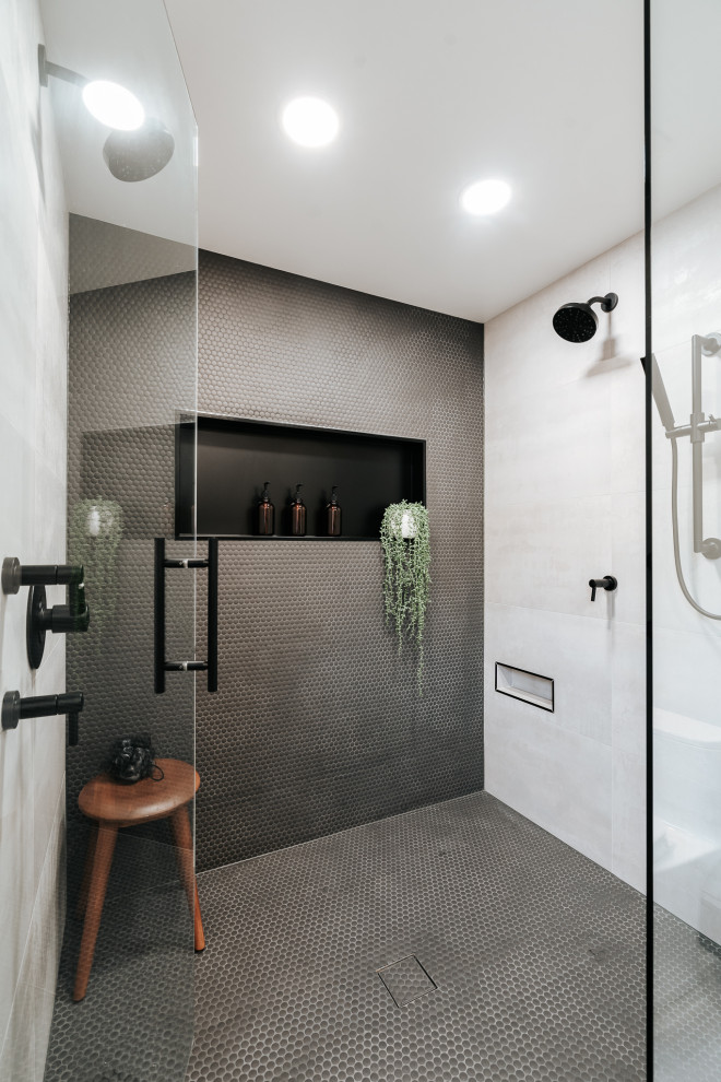 На фото: главная ванная комната среднего размера в стиле модернизм с плоскими фасадами, коричневыми фасадами, двойным душем, унитазом-моноблоком, черной плиткой, цементной плиткой, белыми стенами, полом из цементной плитки, врезной раковиной, столешницей из искусственного кварца, серым полом, душем с распашными дверями, серой столешницей, нишей, тумбой под две раковины и подвесной тумбой с