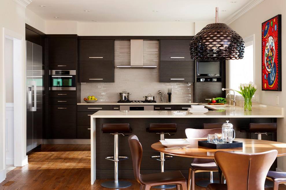 Inspiration for a mid-sized transitional u-shaped medium tone wood floor and brown floor eat-in kitchen remodel in DC Metro with stainless steel appliances, an undermount sink, flat-panel cabinets, white backsplash, a peninsula, dark wood cabinets, quartz countertops and glass tile backsplash
