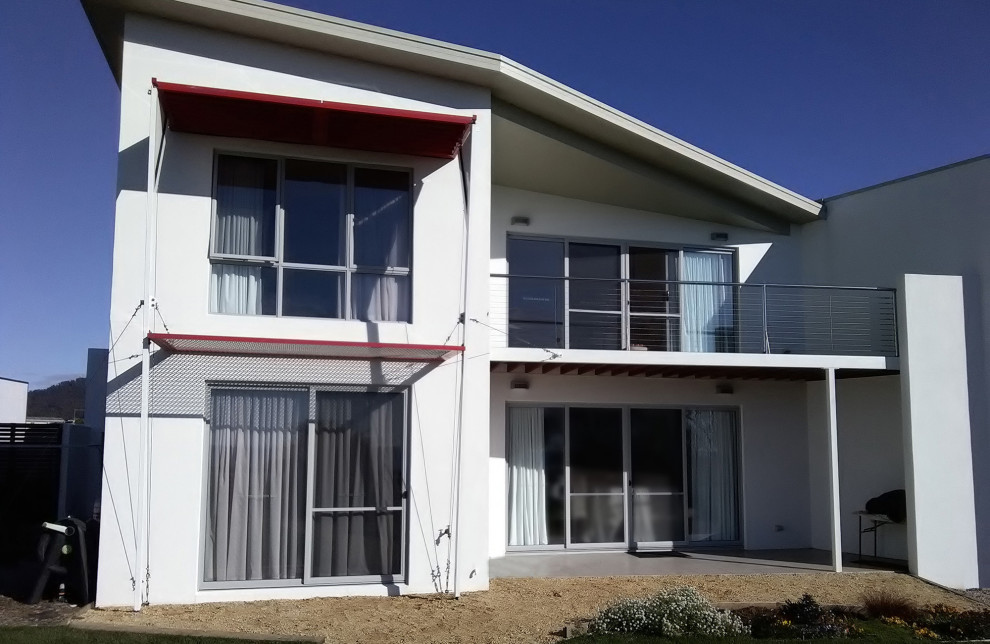 Inspiration for a mid-sized contemporary two-storey white house exterior with a clipped gable roof, a metal roof, concrete fiberboard siding and a white roof.