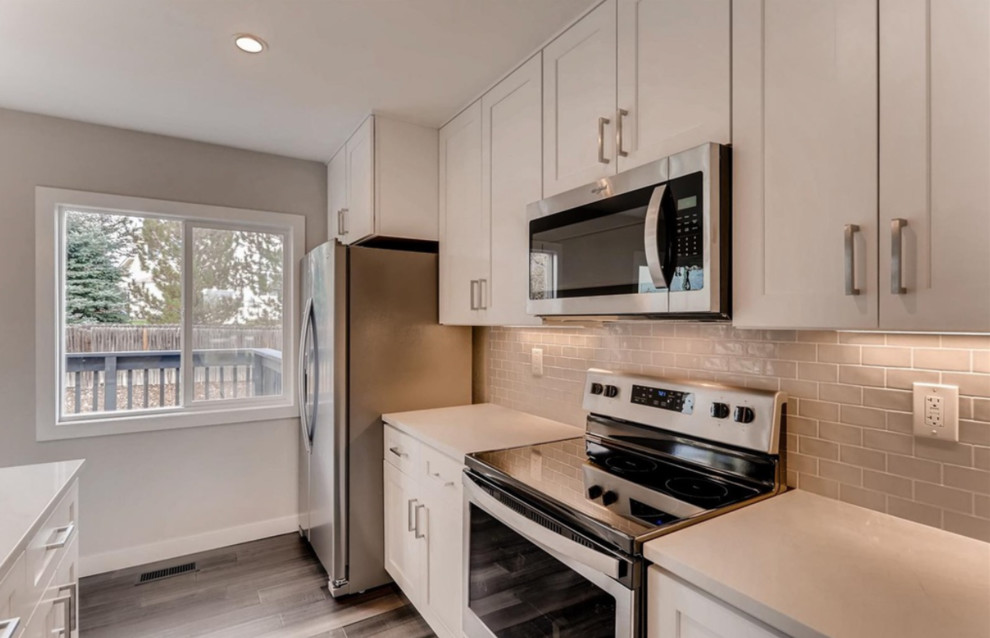 Inspiration for a mid-sized contemporary single-wall medium tone wood floor and brown floor kitchen remodel with an undermount sink, shaker cabinets, white cabinets, gray backsplash, ceramic backsplash, stainless steel appliances, an island and white countertops
