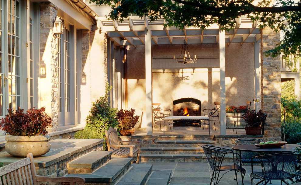 Example of a mid-sized classic backyard stone patio design in DC Metro with a pergola