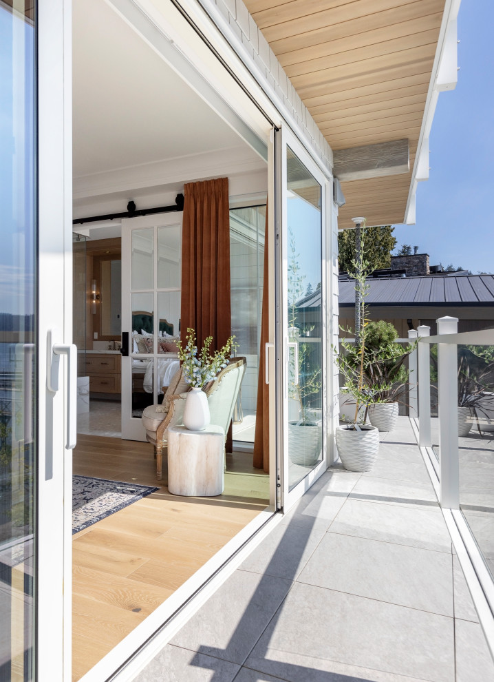 Photo of a beach style balcony in Vancouver with a roof extension and glass railing.