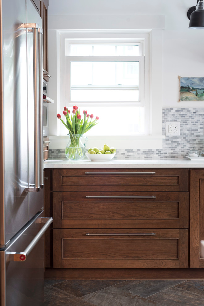Inspiration for a mid-sized transitional u-shaped vinyl floor and multicolored floor kitchen remodel with an undermount sink, shaker cabinets, brown cabinets, quartz countertops, gray backsplash, marble backsplash, stainless steel appliances, no island and white countertops