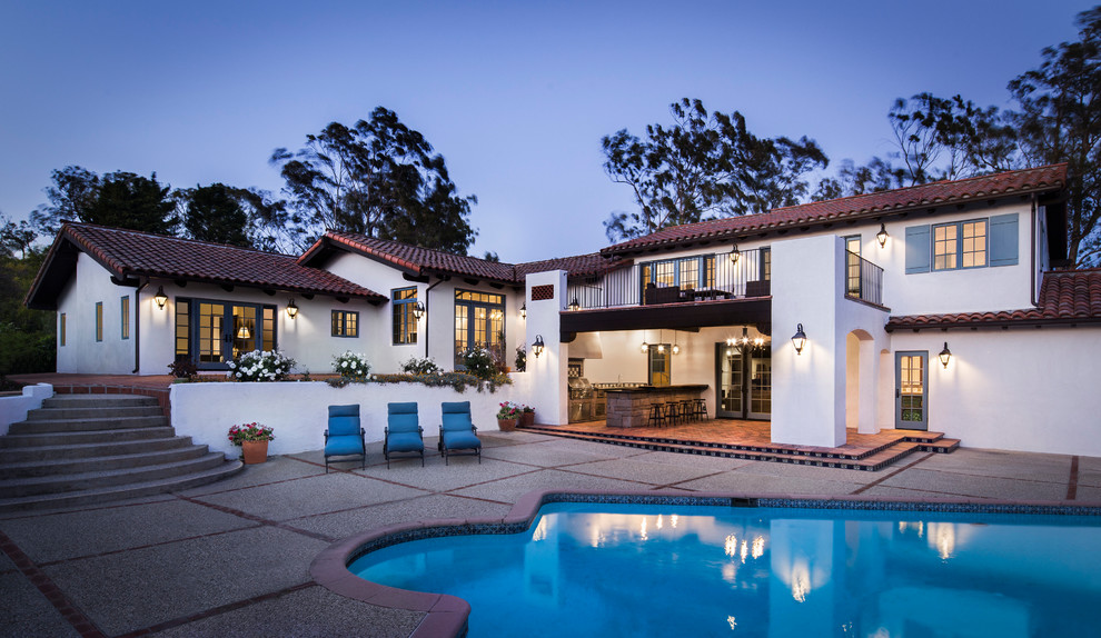 Large mediterranean backyard custom-shaped lap pool in Santa Barbara with concrete pavers.