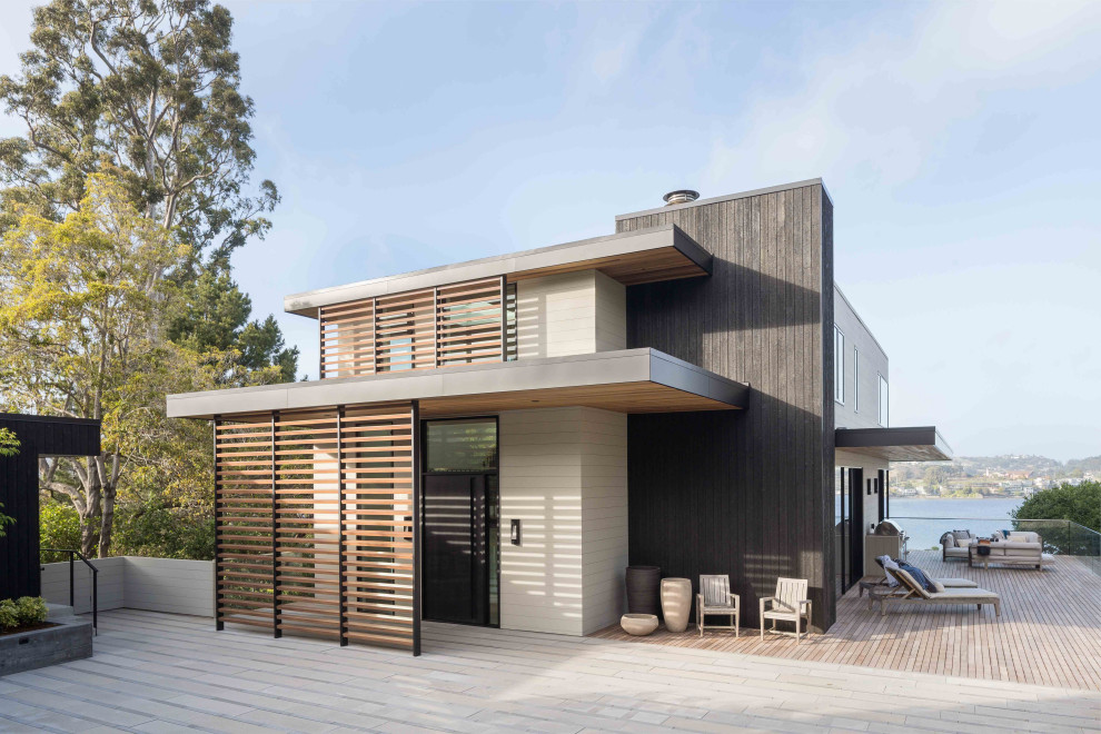 Photo of a small contemporary two-storey black house exterior in San Francisco with wood siding, a flat roof, a metal roof and a grey roof.