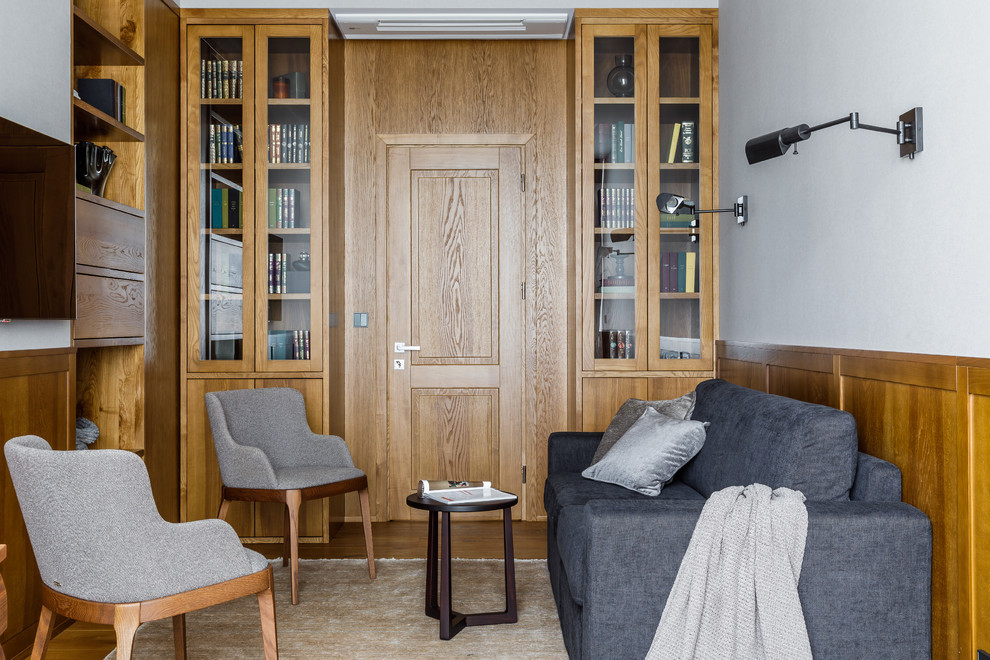 Photo of a mid-sized contemporary home office in Moscow with a library, grey walls, laminate floors and brown floor.