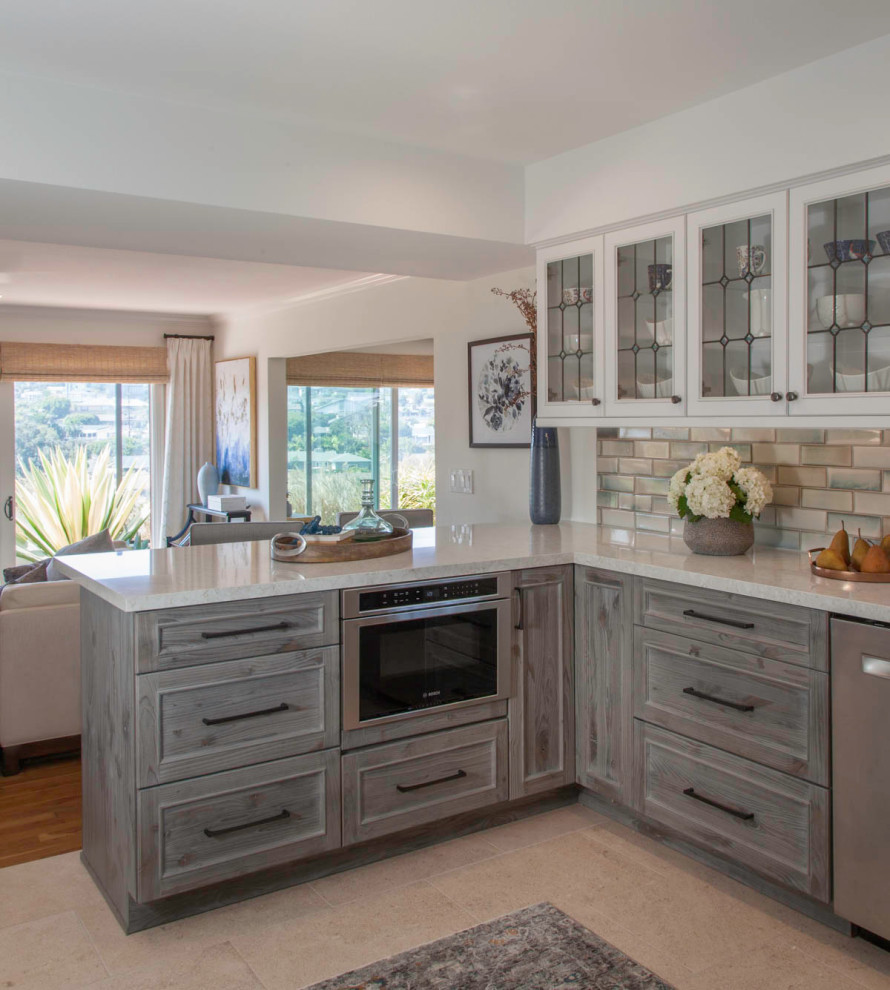 This is an example of a mid-sized transitional u-shaped eat-in kitchen in San Diego with an undermount sink, shaker cabinets, distressed cabinets, quartz benchtops, blue splashback, ceramic splashback, stainless steel appliances, porcelain floors, a peninsula, beige floor and turquoise benchtop.