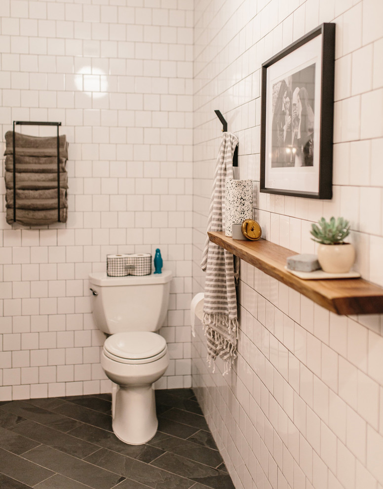 This is an example of a mid-sized contemporary powder room in Austin with a one-piece toilet, white tile, ceramic tile, white walls, marble floors and black floor.