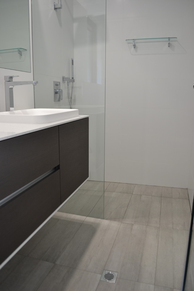 This is an example of a small contemporary master bathroom in Perth with dark wood cabinets, a curbless shower, a one-piece toilet, gray tile, porcelain tile, white walls, porcelain floors, a drop-in sink and engineered quartz benchtops.